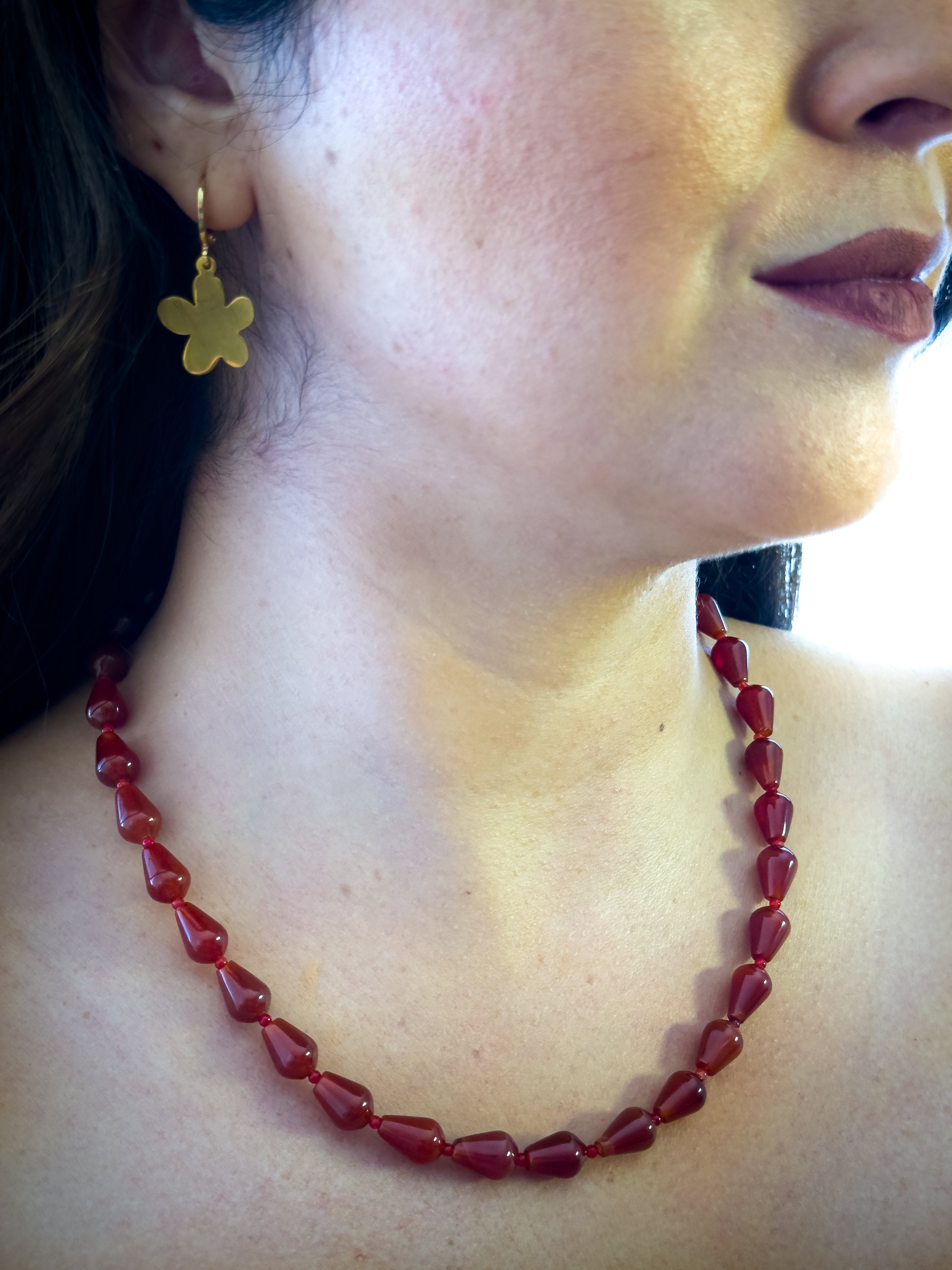 Mujer usando collar de cornalina natural en forma de gota de la marca MAVIS.