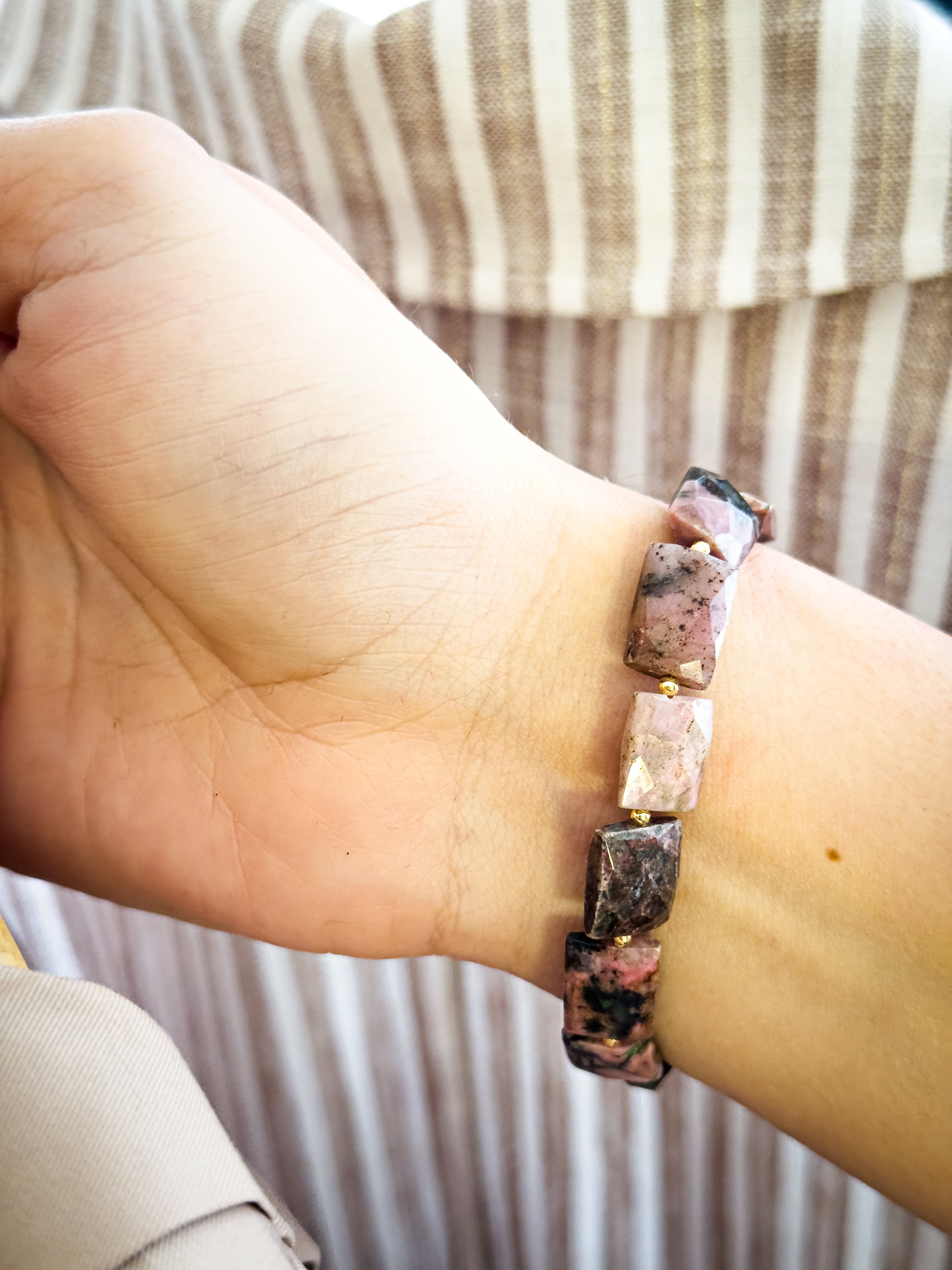 Pulsera de Rodonita natural facetada sobre la muñeca, mostrando sus bloques geométricos y las vetas minerales naturales características.